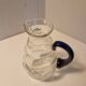 Glass carafe with wavy body and blue handle