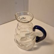 Glass carafe with wavy body and blue handle