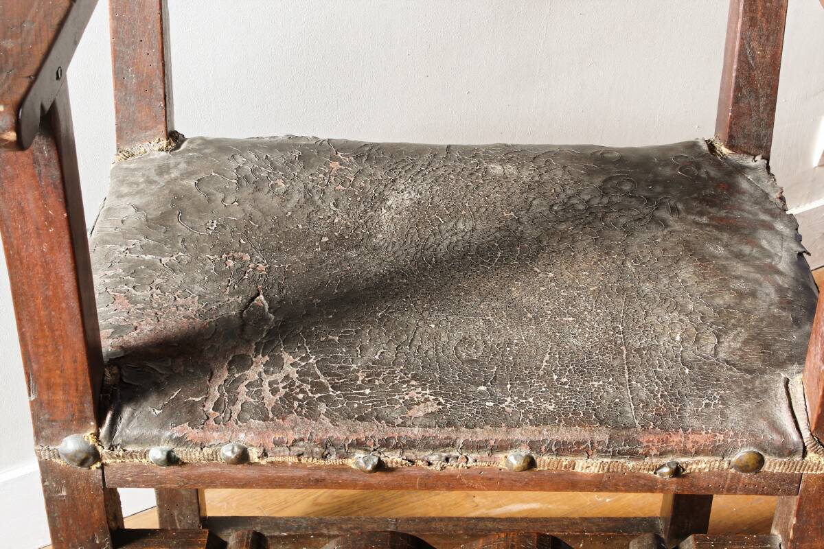 Antique armchair in walnut and studded leather, 17th century