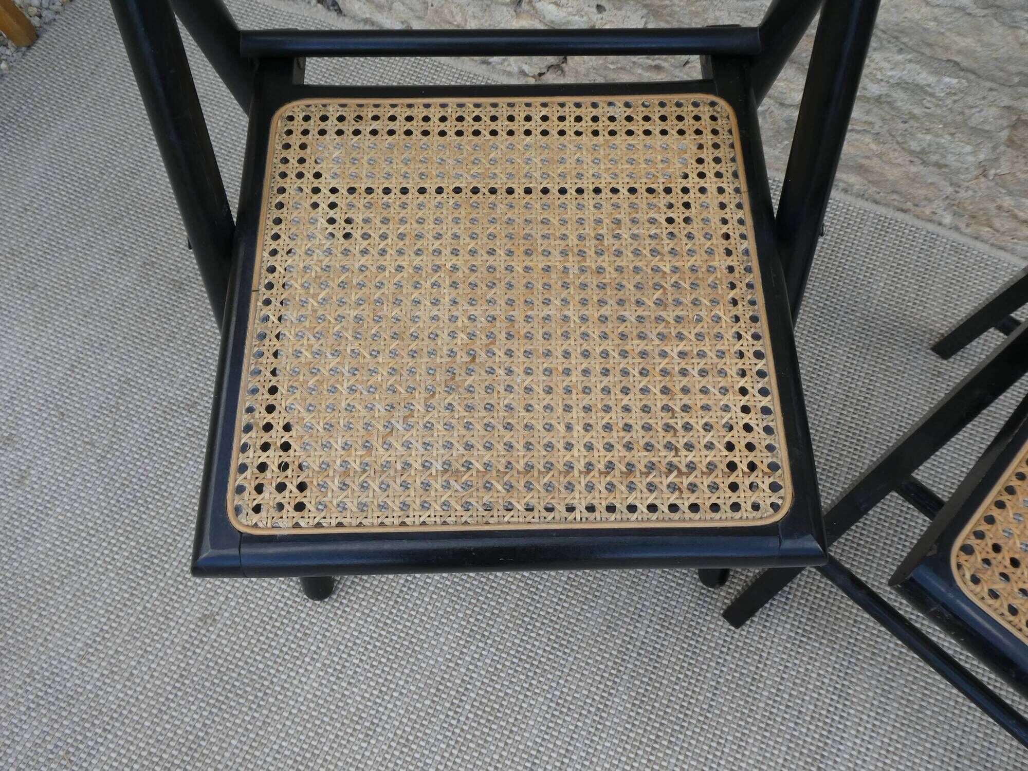 Paire de chaises pliantes en bois noirci et assise cannée