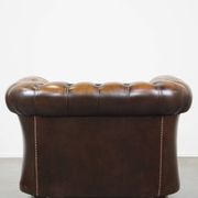 A well-maintained cowhide leather English Chesterfield armchair