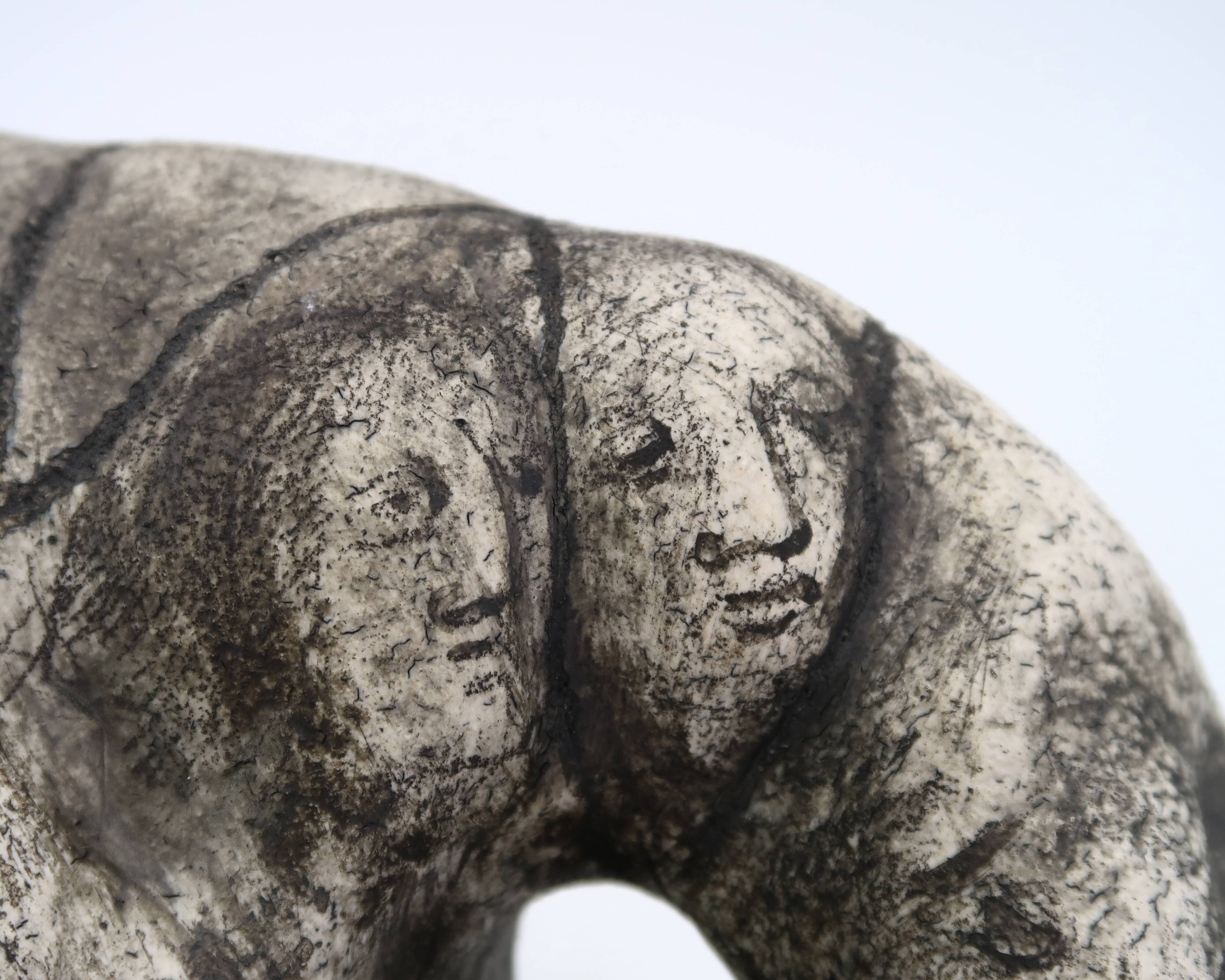 Ceramic vase sculpture decorated with faces and featuring a hole, 1980s.