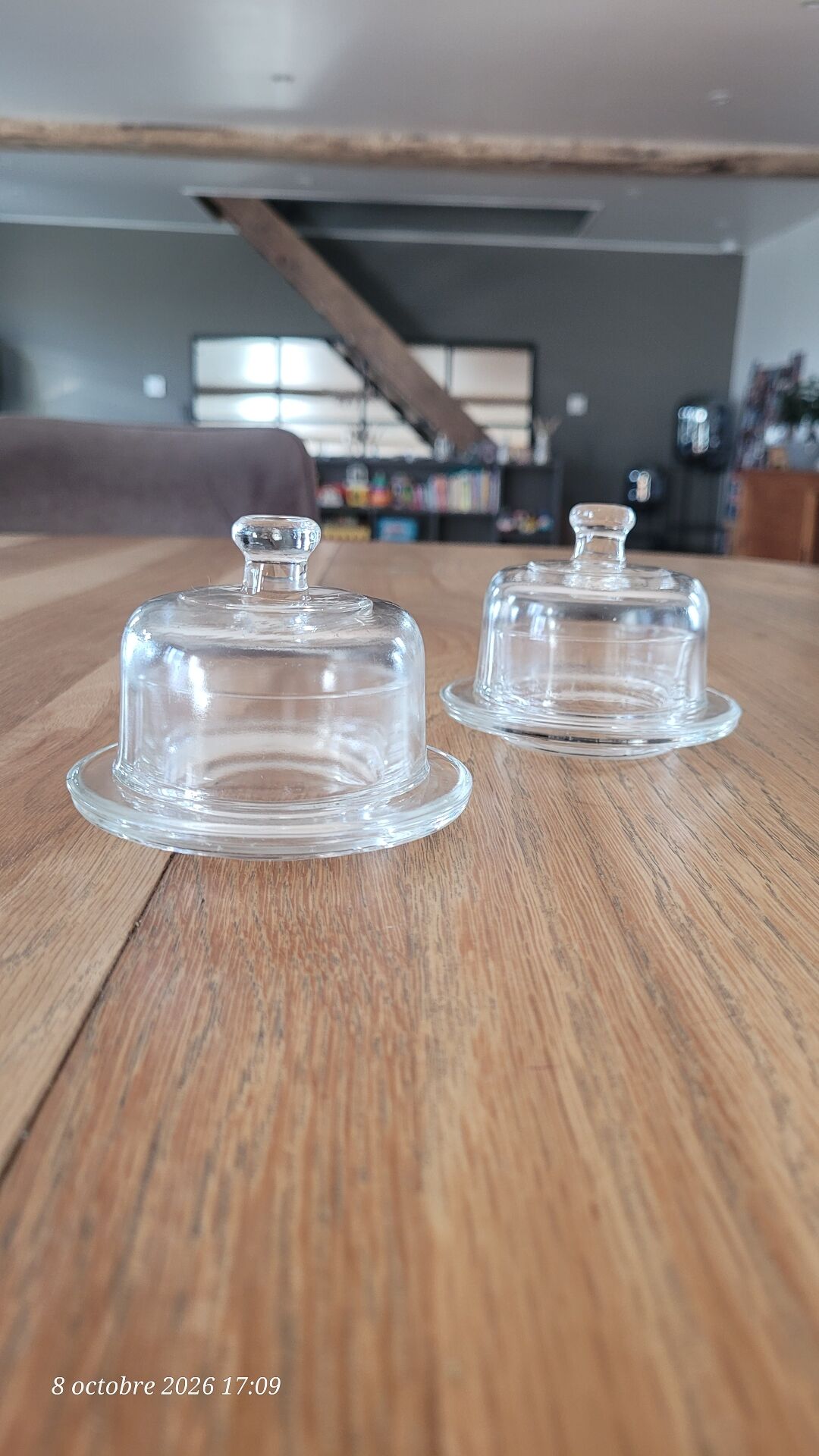 2 transparent glass butter dishes accompanied by their matching cloches.