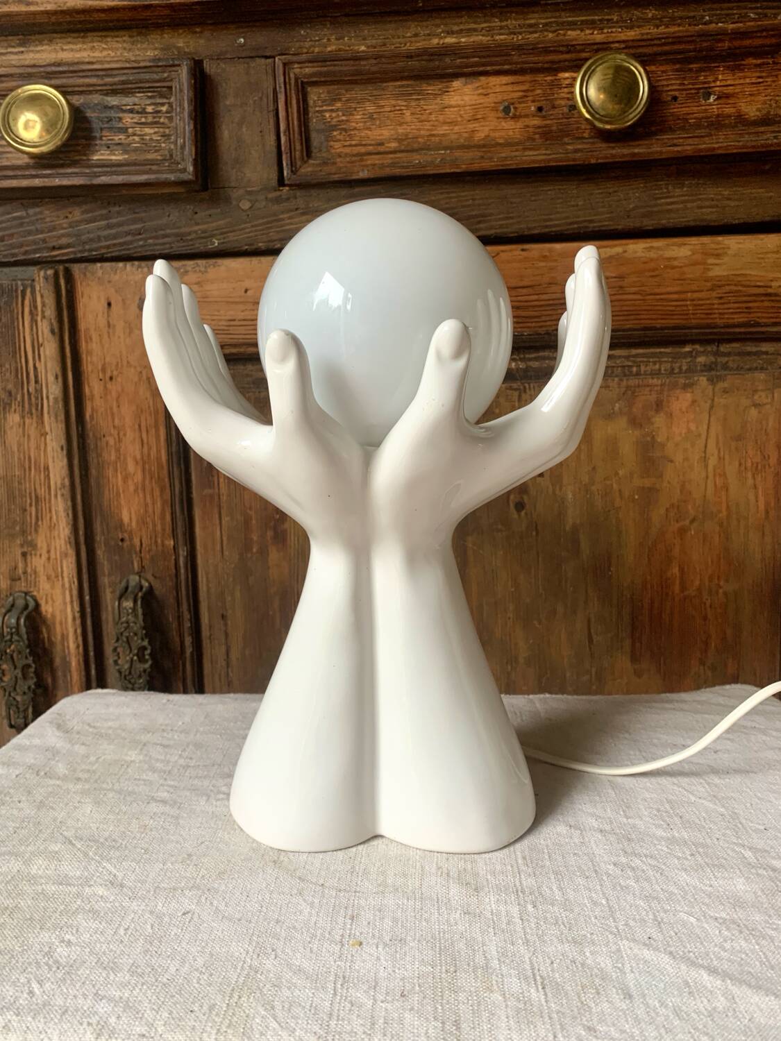 Ceramic table lamp depicting two hands holding a globe, 1980