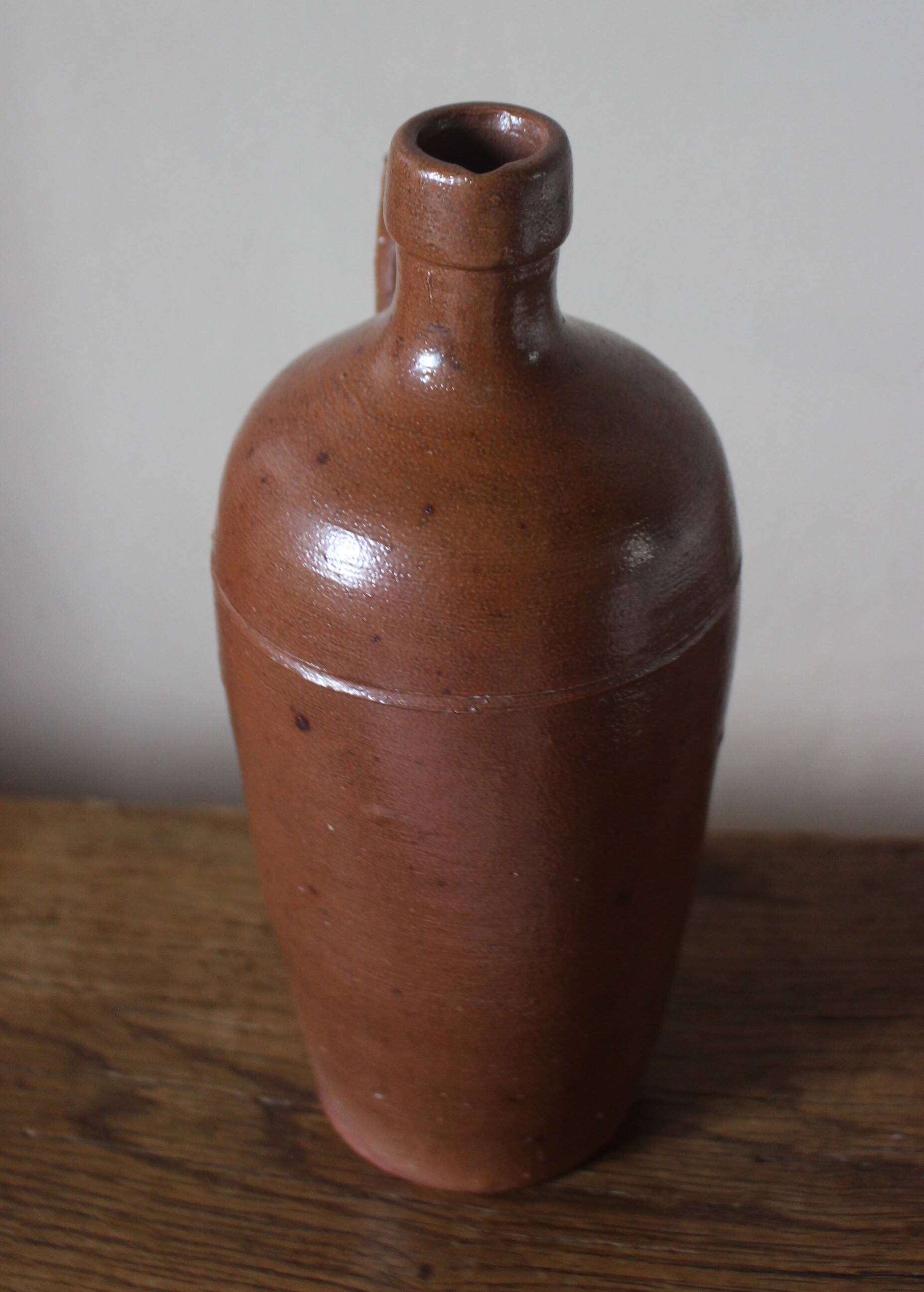 Vintage stoneware liqueur bottle with handle and spout.