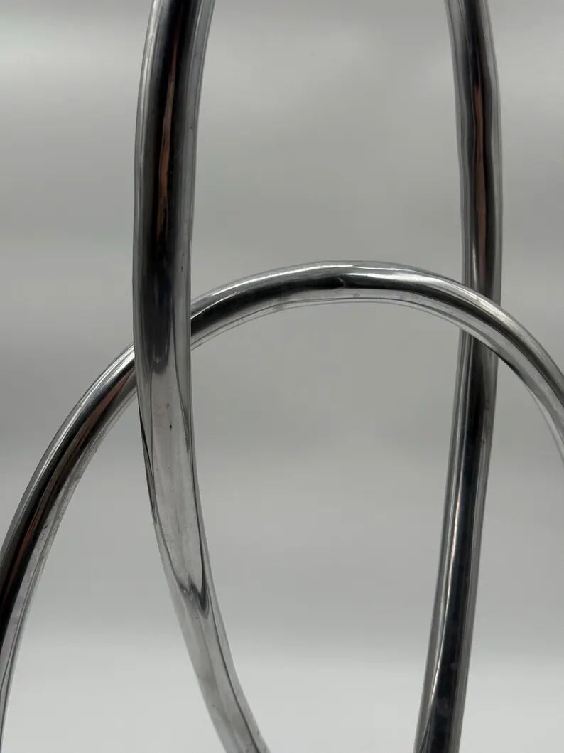 Chromed sculptural art object, abstract modernist shape in metal, contemporary design accent, brutalist interior decoration.