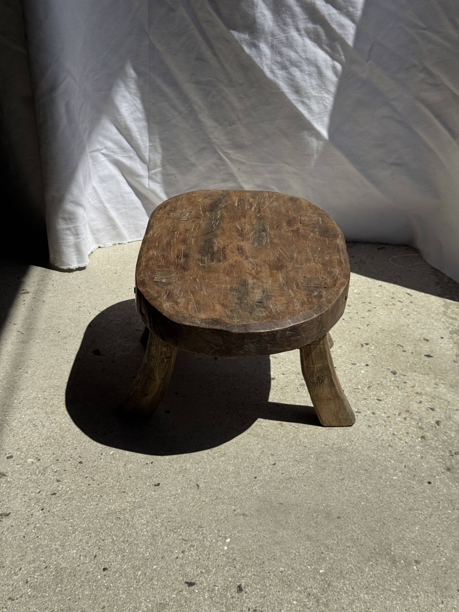 Small stool, oval solid teak side table with curved legs in wabi-sabi style.
