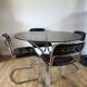 Set consisting of a table in chrome and smoked glass and its 4 tubular chairs in chrome and skaï a