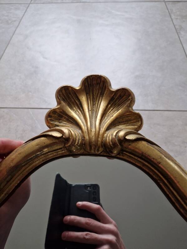 Carved and gilded wooden mirror, the pediment decorated with a shell.