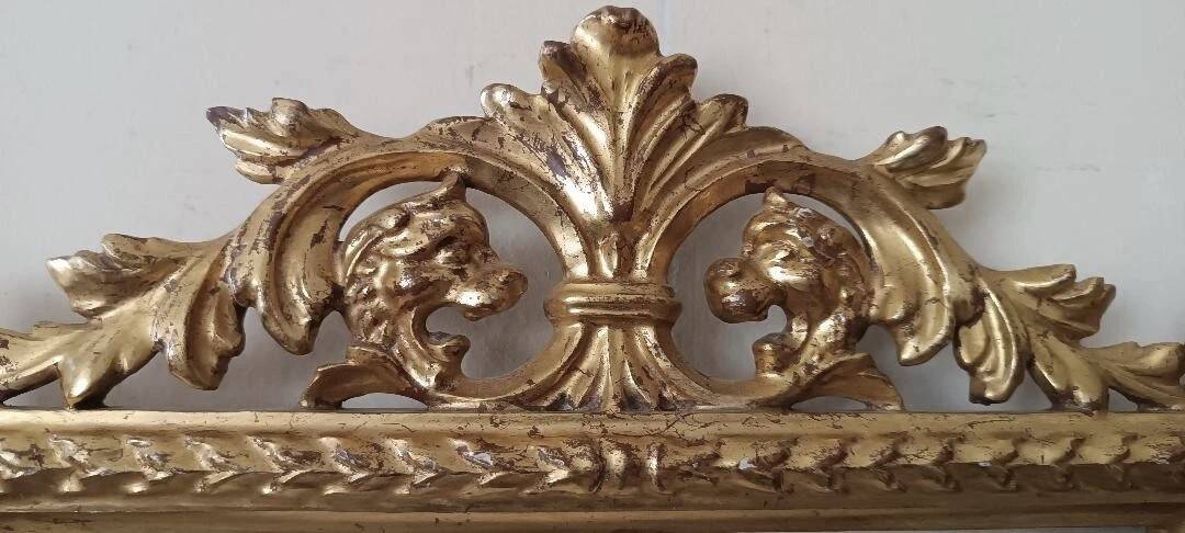 Mirror with a carved wooden frame in an antique style in pure gold.
