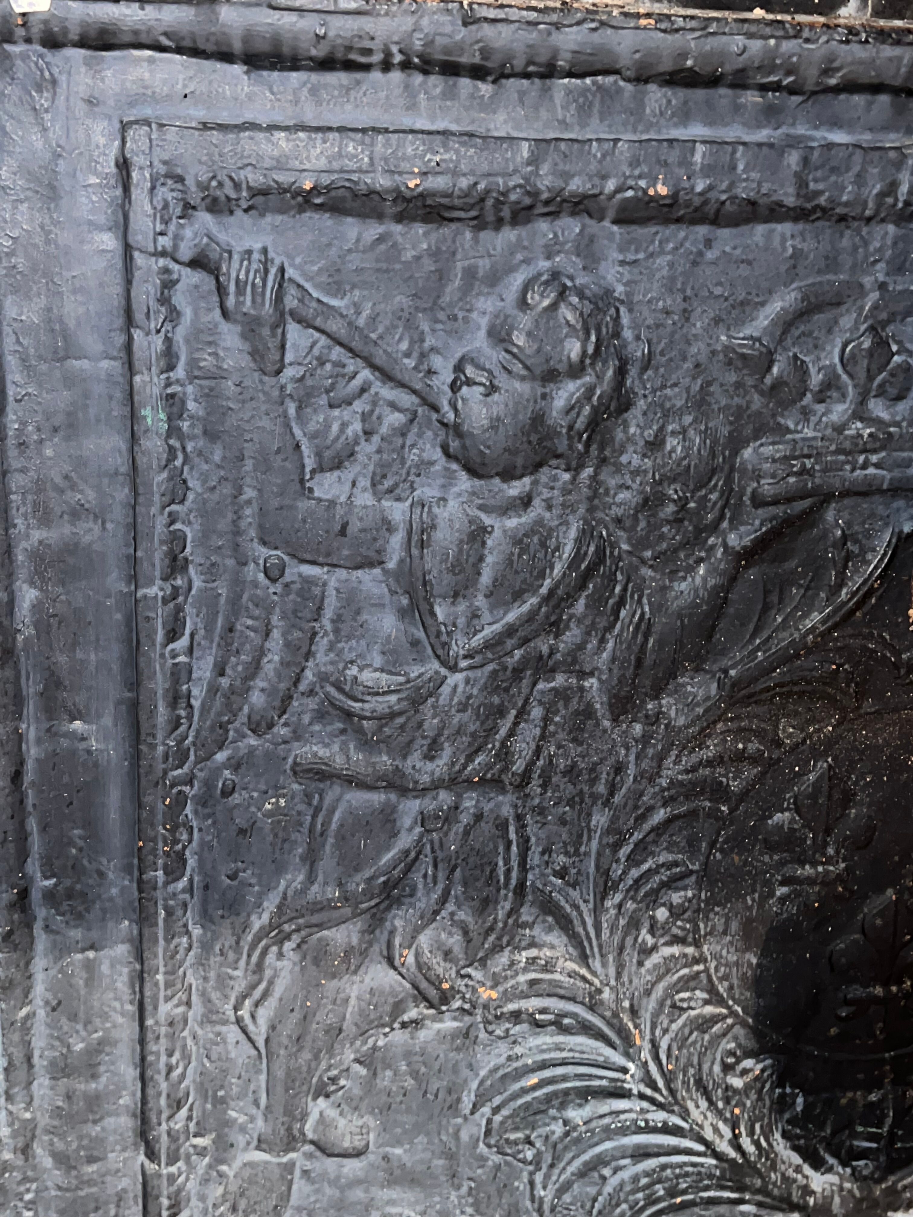 huge old fireplace plate has decoration of angels, crown and fleurs-de-lis