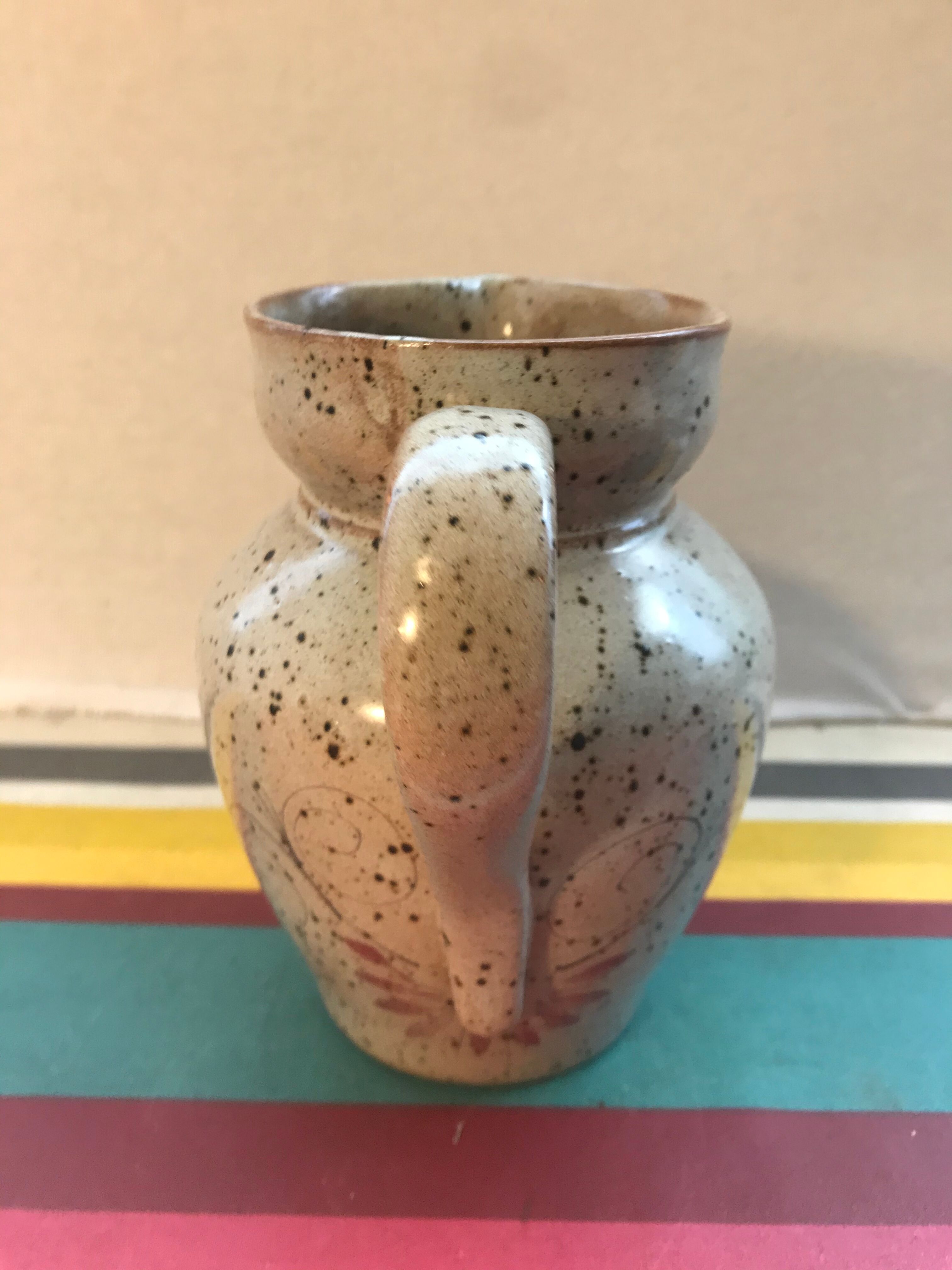 Old gray pitcher with black drawings and vintage stamped handle