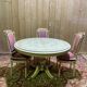 Louis XVI dining room table set with painted wood, gold accents, and pink velvet.