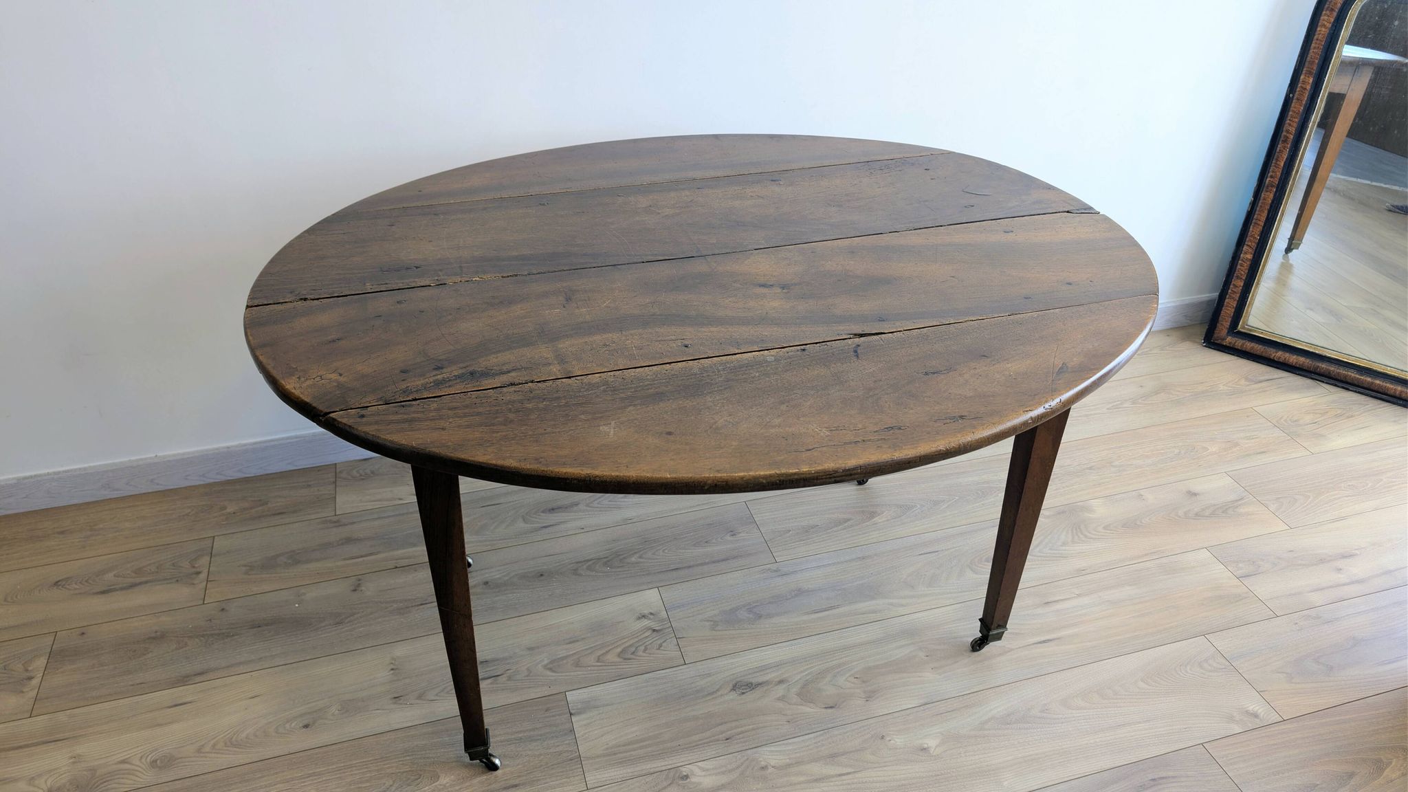 Antique wooden folding table with a patina and brass wheels.