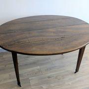 Antique wooden folding table with a patina and brass wheels.