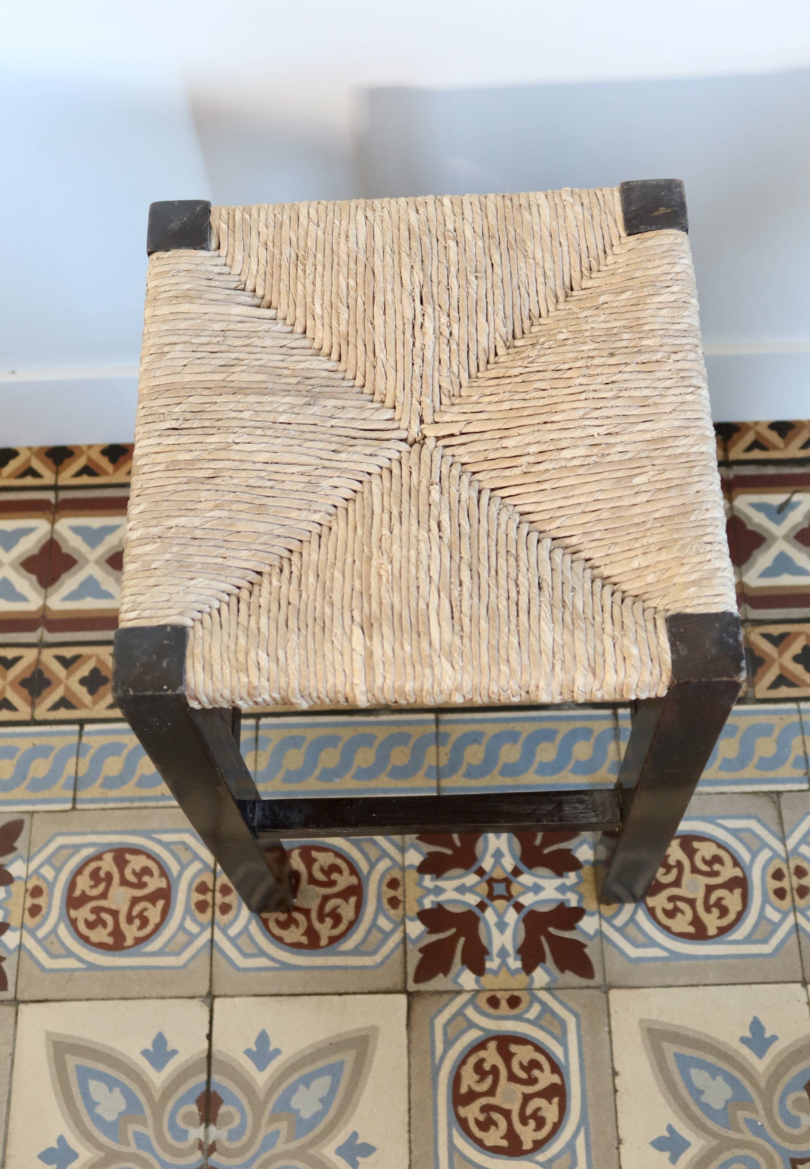 Vintage rustic stool in wood with a straw seat.