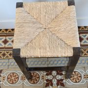 Vintage rustic stool in wood with a straw seat.