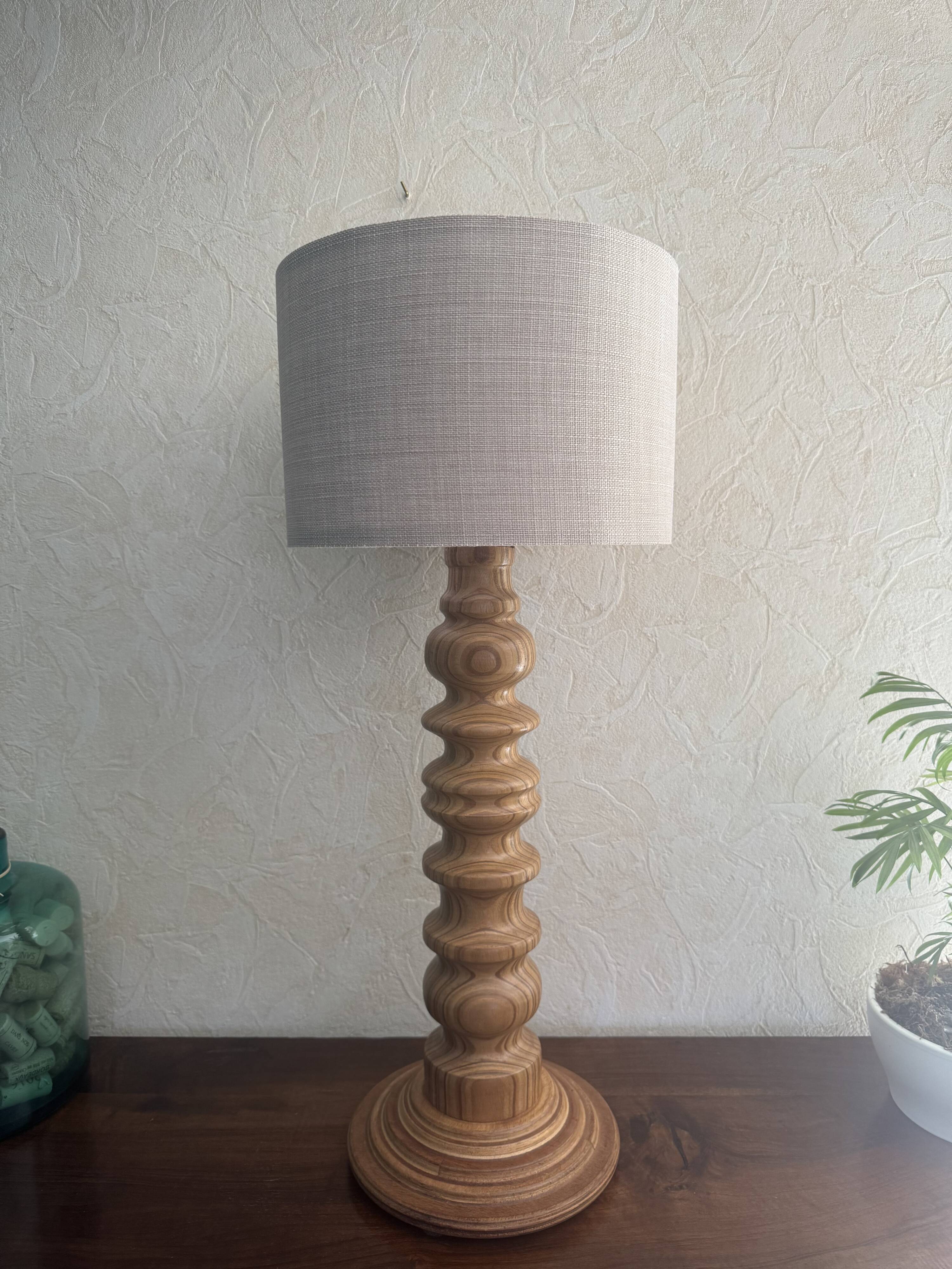 Wooden turned totem lamp with a linen shade in a vintage Scandinavian style.