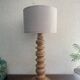 Wooden turned totem lamp with a linen shade in a vintage Scandinavian style.