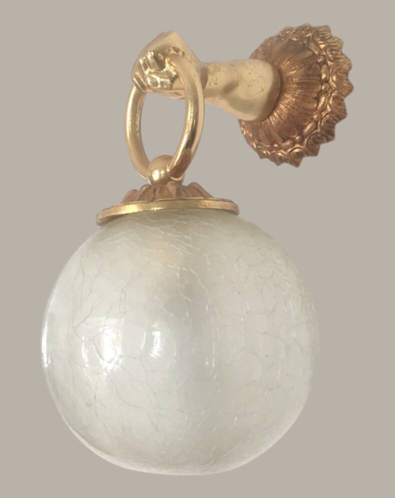Wall light with golden hand and glass globe