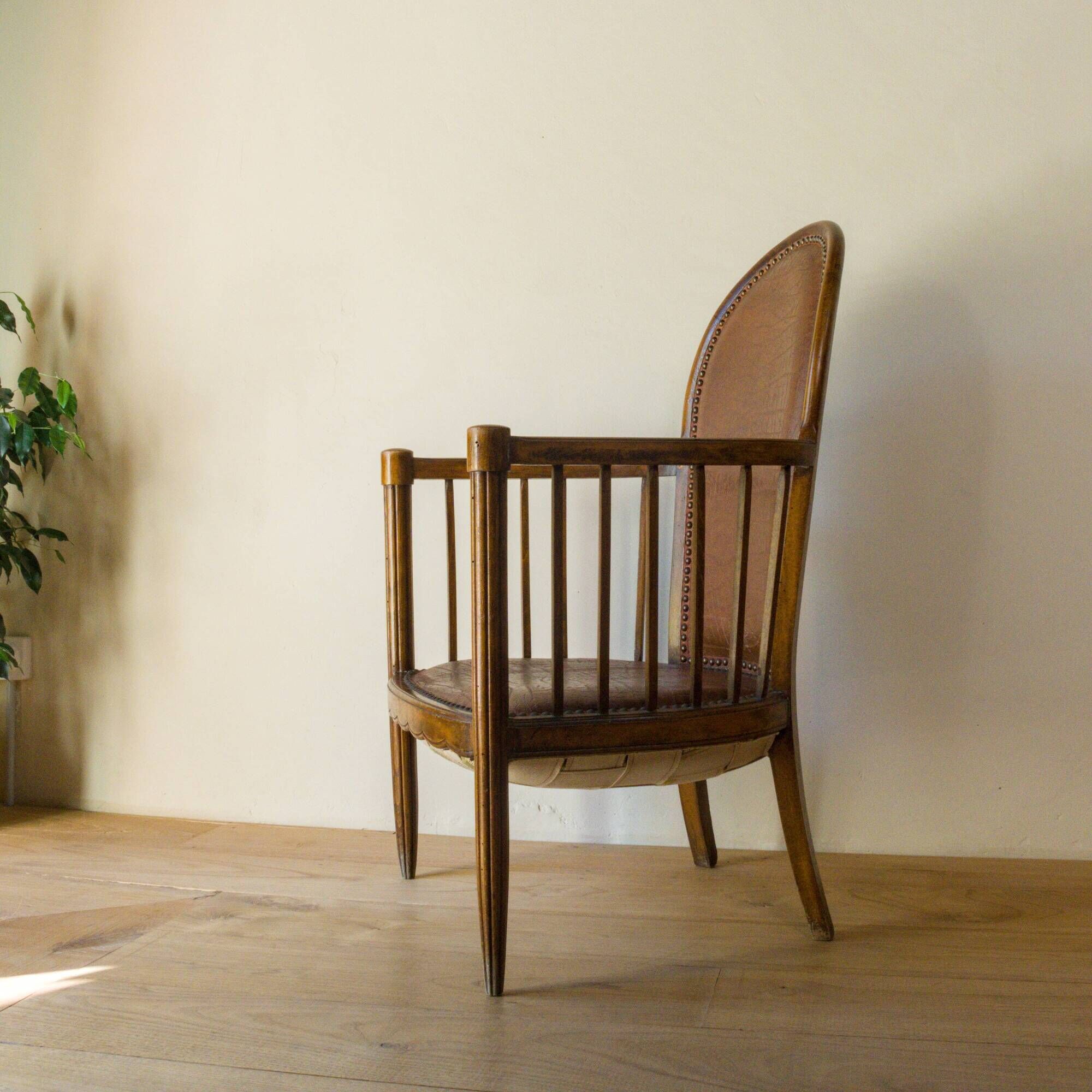 Antique armchair in solid wood and patinated brown leather, early 20th century.