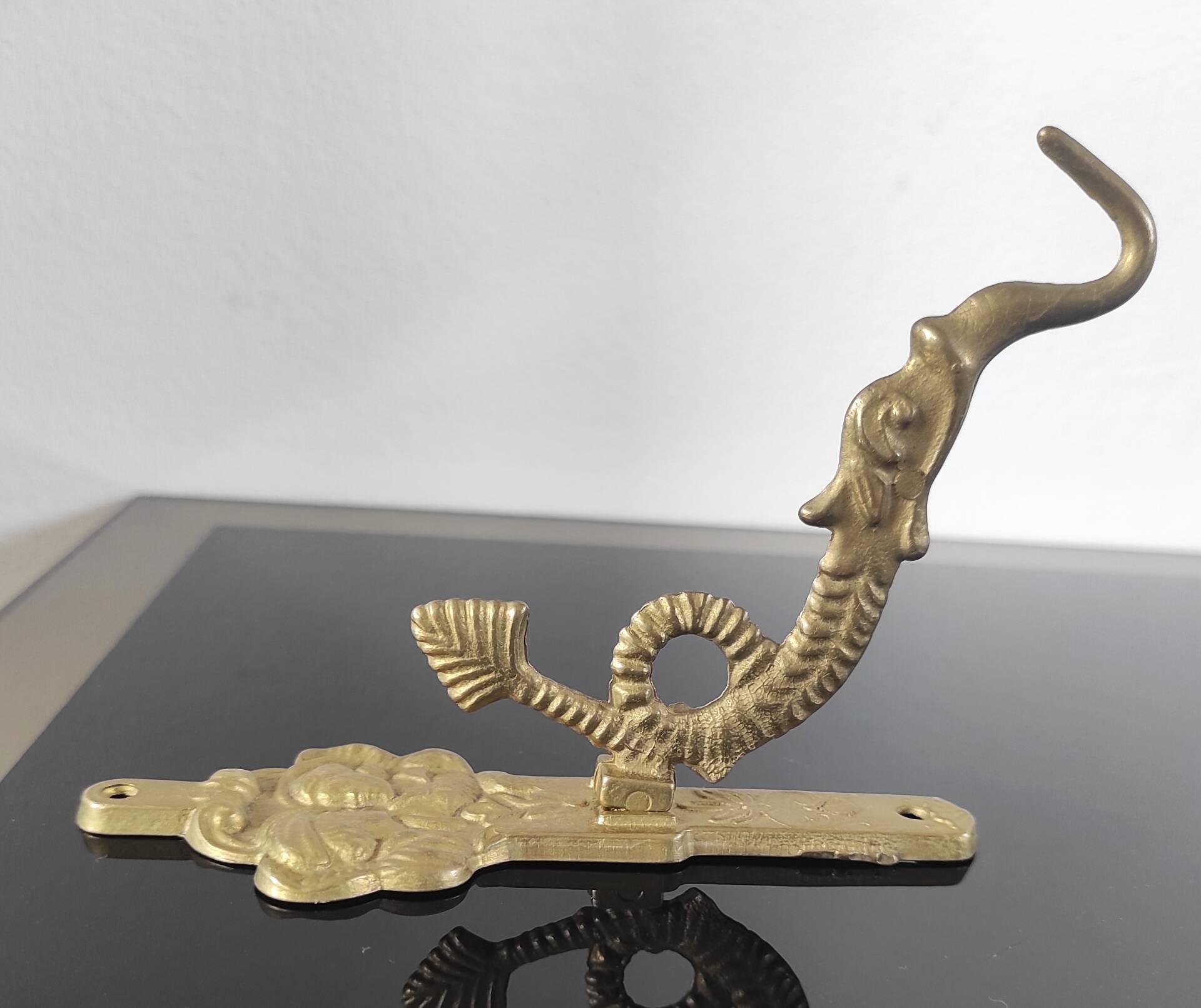 Vintage brass coat hook with marine creature motif and medallion.
