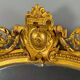 Large antique gilded wooden mirror in Louis XVI style with a sculpted pediment, 19th century.