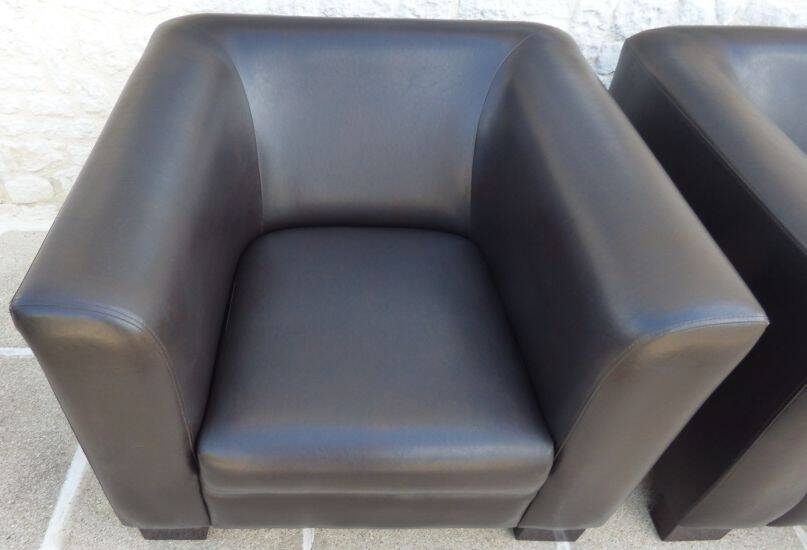2 club armchairs with a chocolate faux leather seat and backrest and wooden legs.
