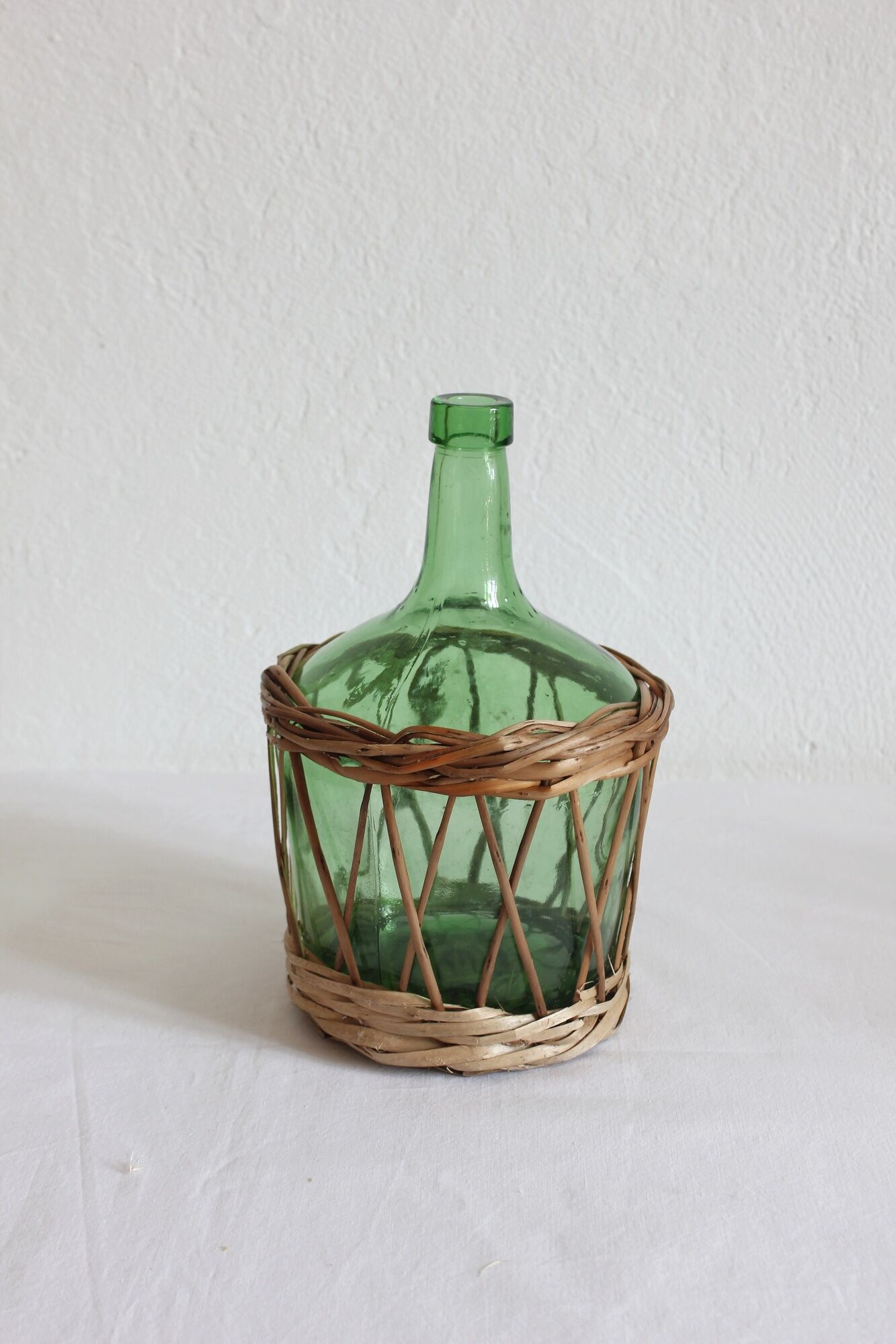 Dame jeanne verte vintage entourée de rotin / osier