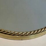 Oval brass mirror surrounded by a cord.