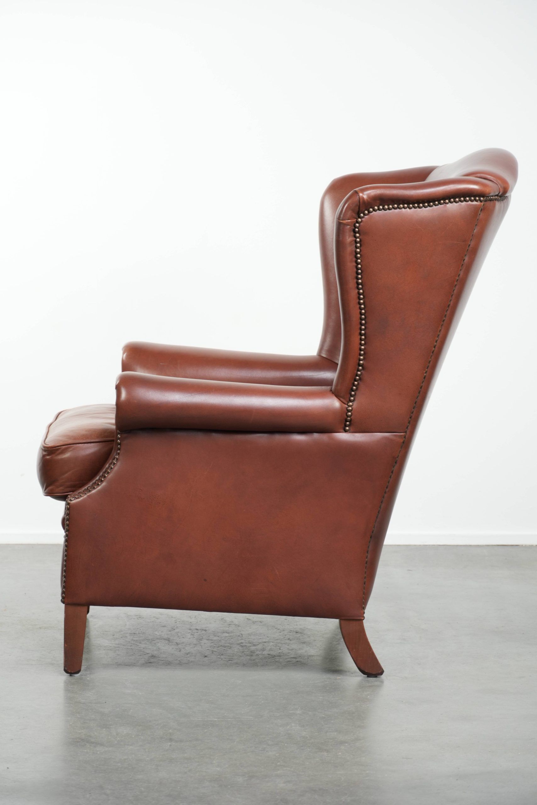 Cognac-coloured cow leather wingback armchair in English style
