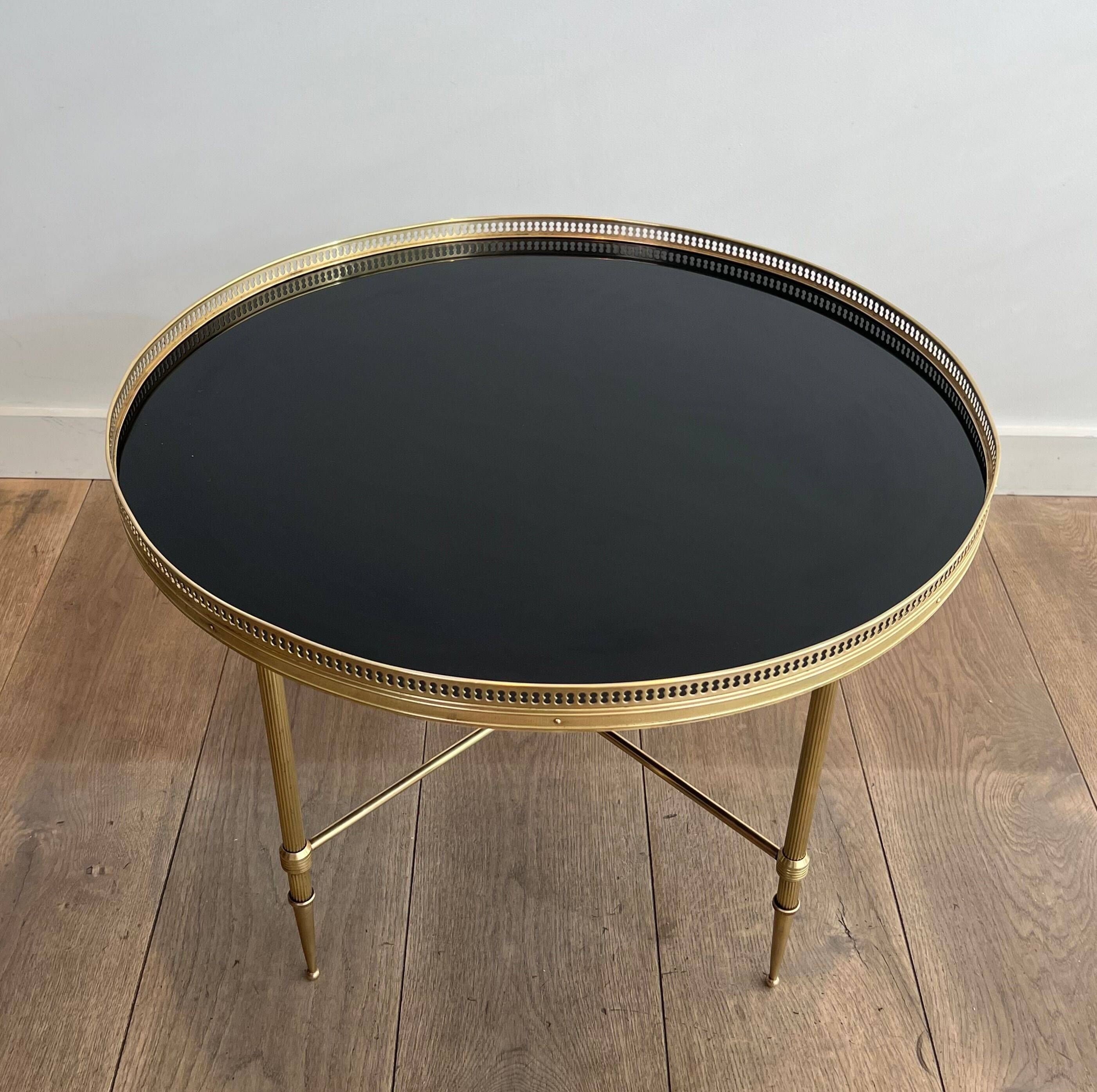 Round coffee table in brass with a black lacquered glass top from Maison Jansen.