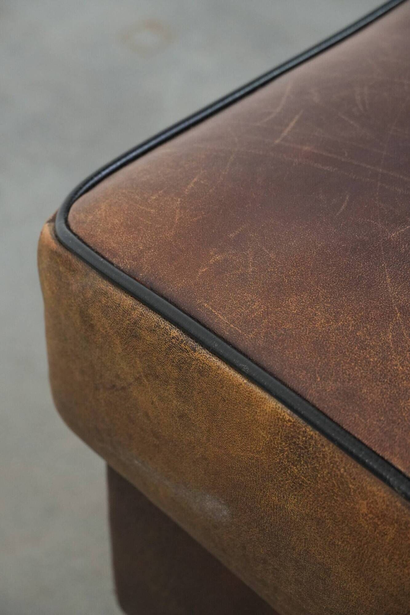 Sturdy vintage sheepskin ottoman in a beautiful large size with black piping