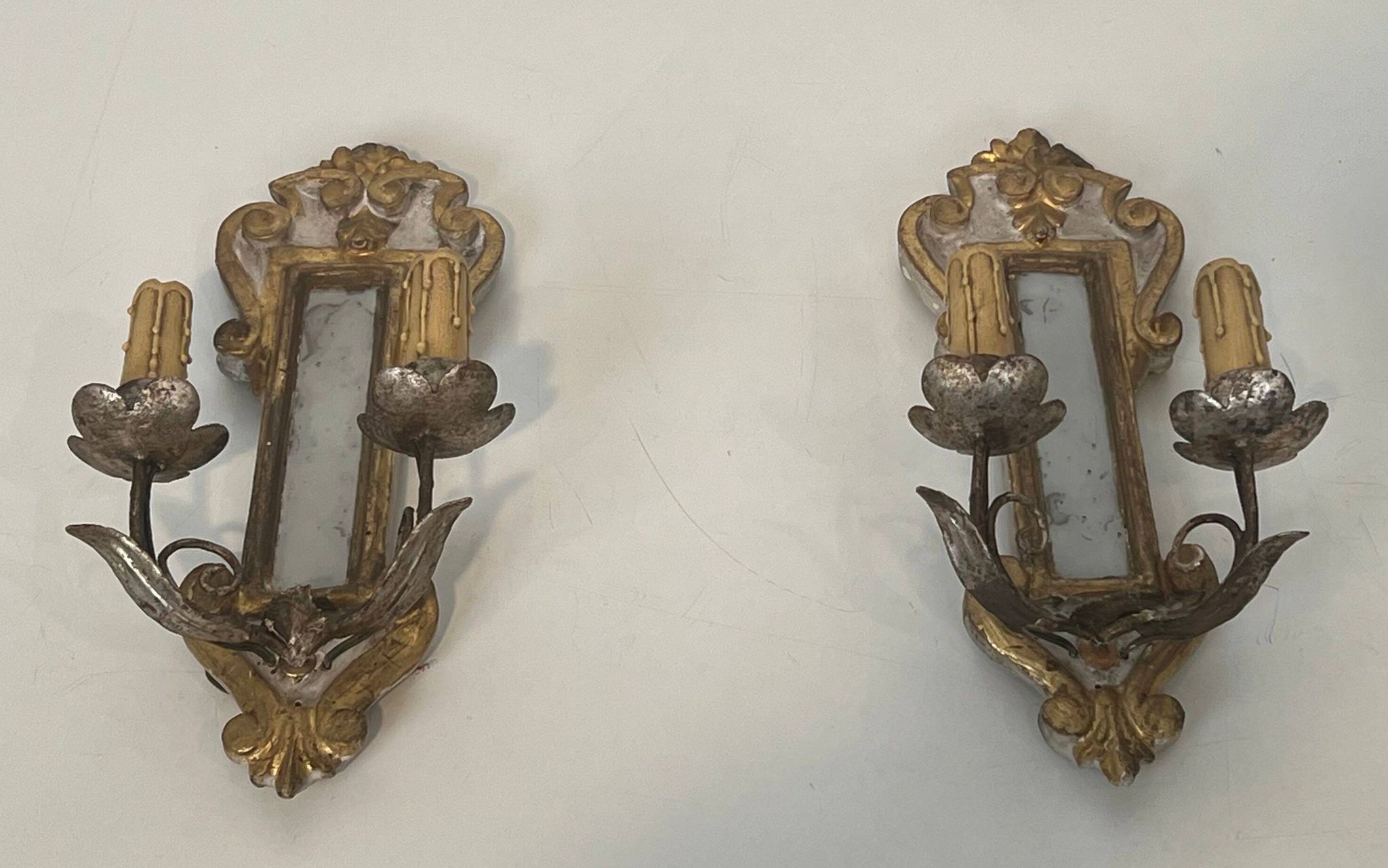 Pair of wall sconces in carved wood and silvered and gilded patinated metal with a central mirror.