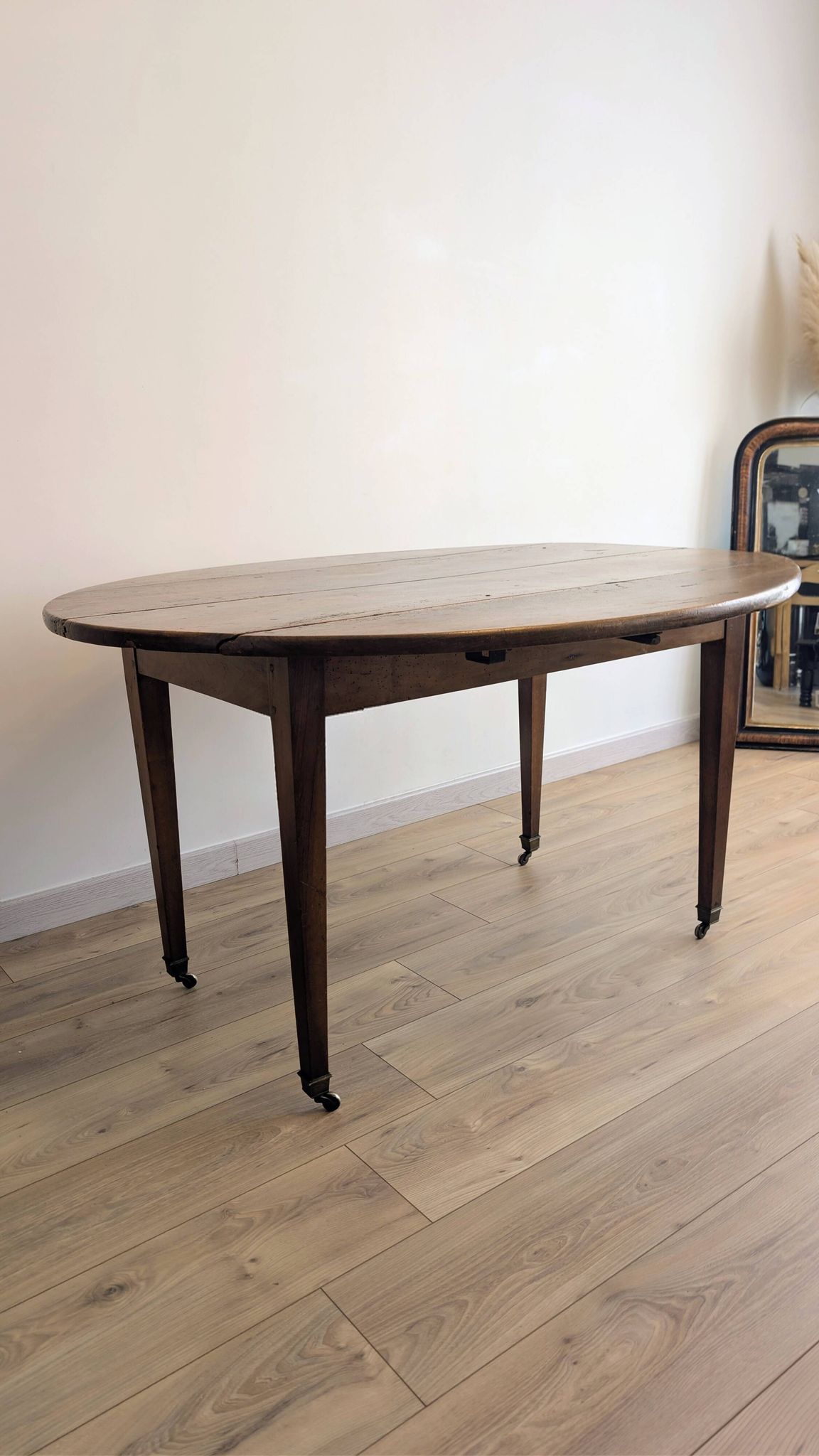 Antique wooden folding table with a patina and brass wheels.
