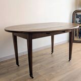 Antique wooden folding table with a patina and brass wheels.