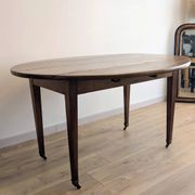 Antique wooden folding table with a patina and brass wheels.