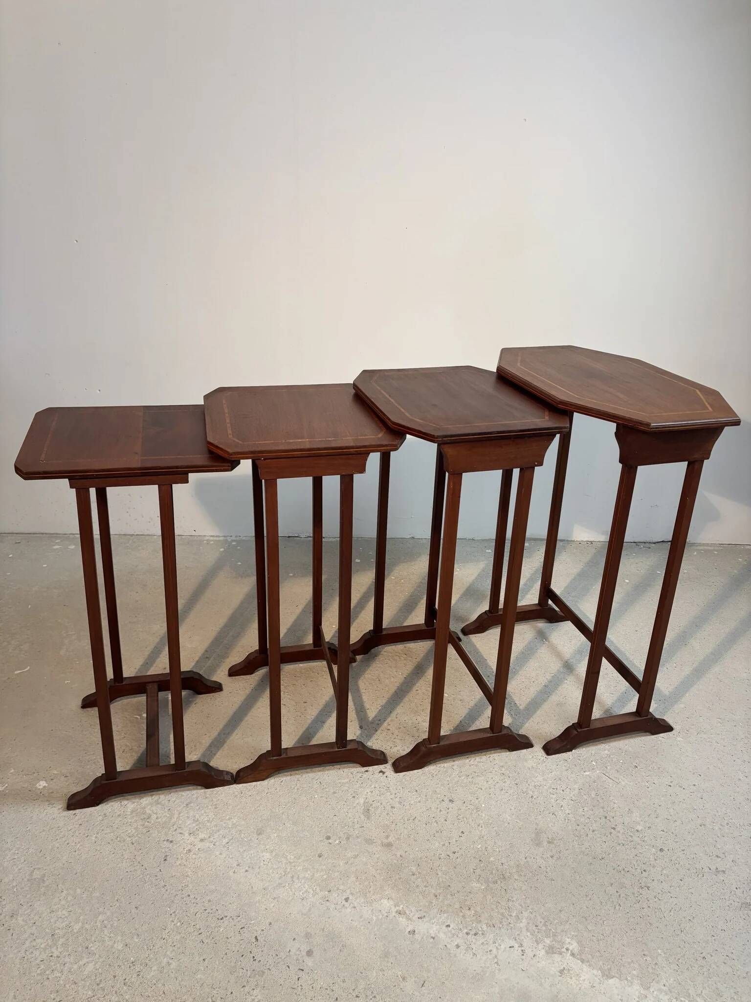 Four nesting tables with polygonal tops and decorative inlays.