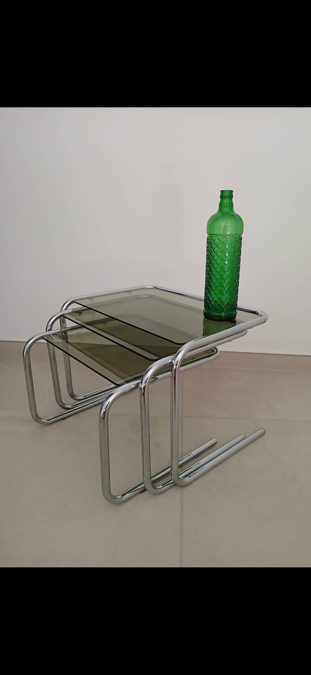 Nest tables in chrome metal and tinted glass.