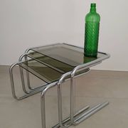 Nest tables in chrome metal and tinted glass.