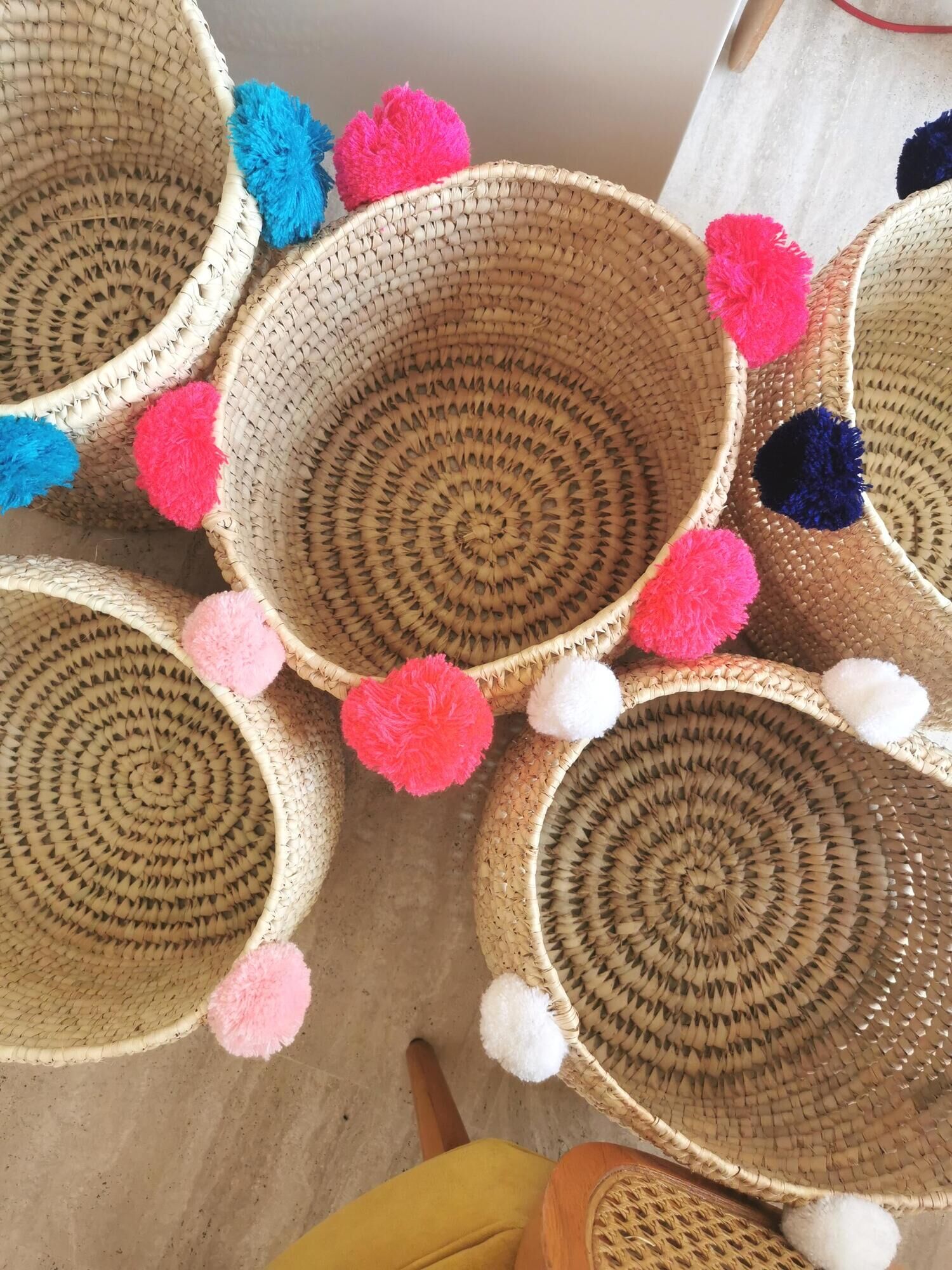 Moroccan basket with pale pink pompoms made of palm fiber