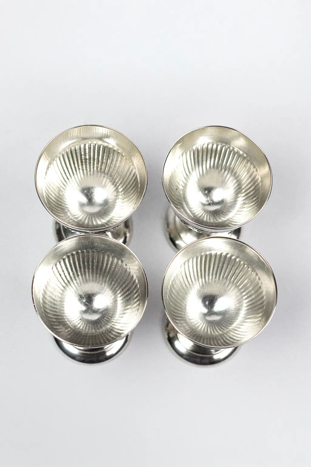 Four silver-plated Christofle egg cups with fluted sides.