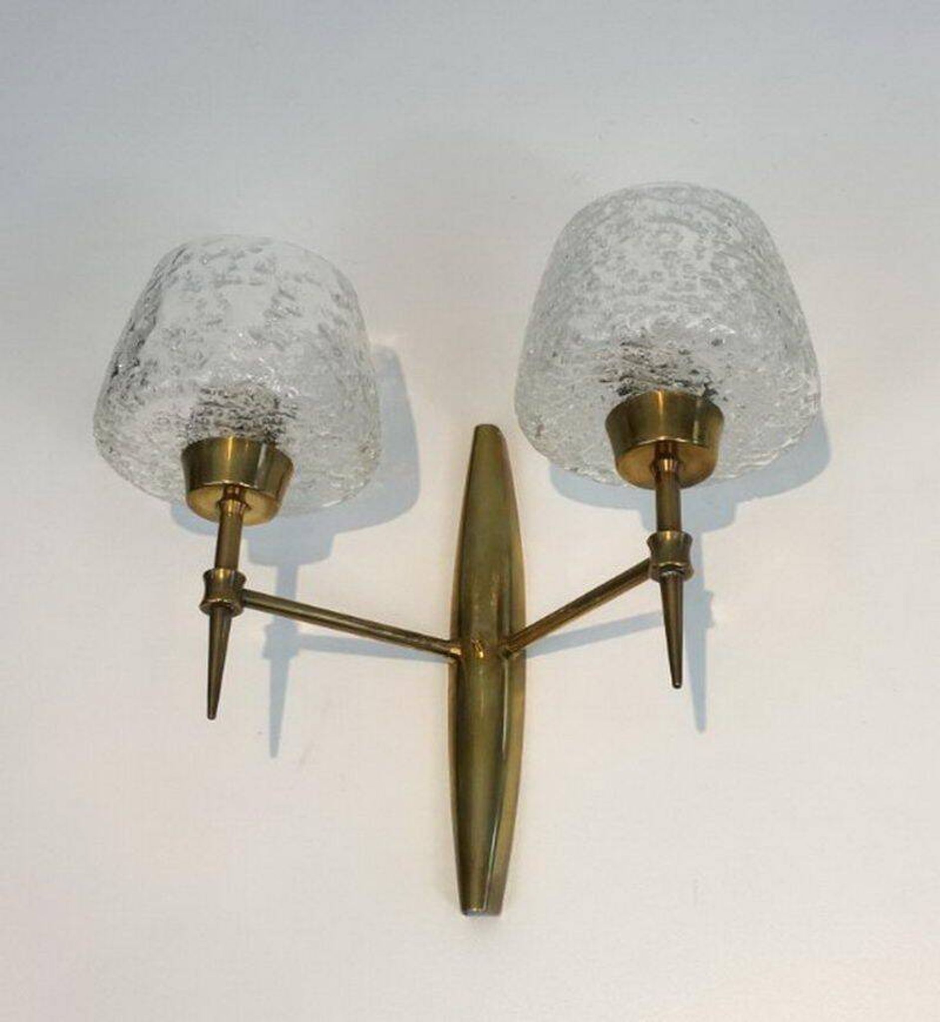 Pair of bronze wall sconces with worked glass reflectors. Stilnovo