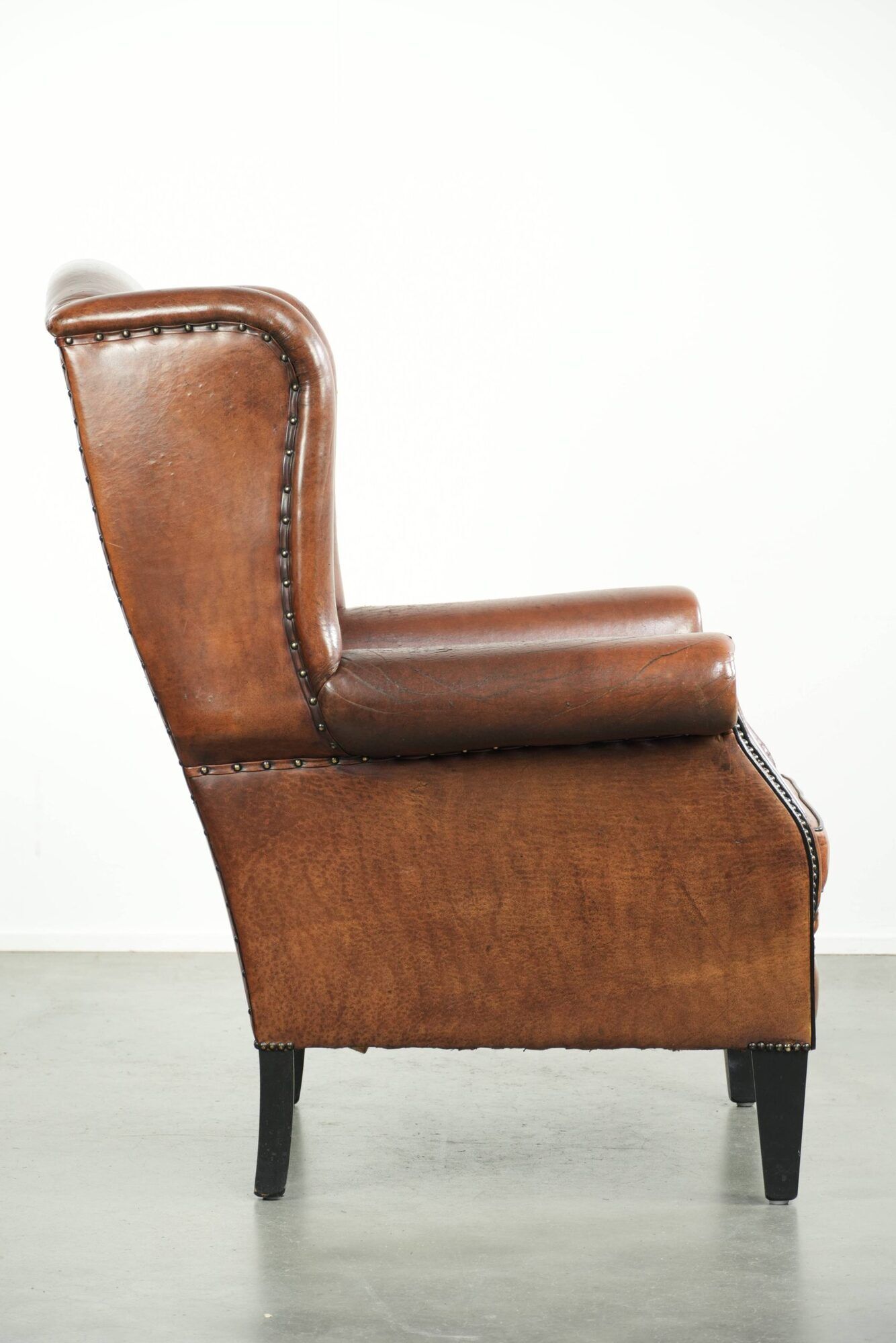 Sheepskin wingback armchair finished with black piping and a correct seat