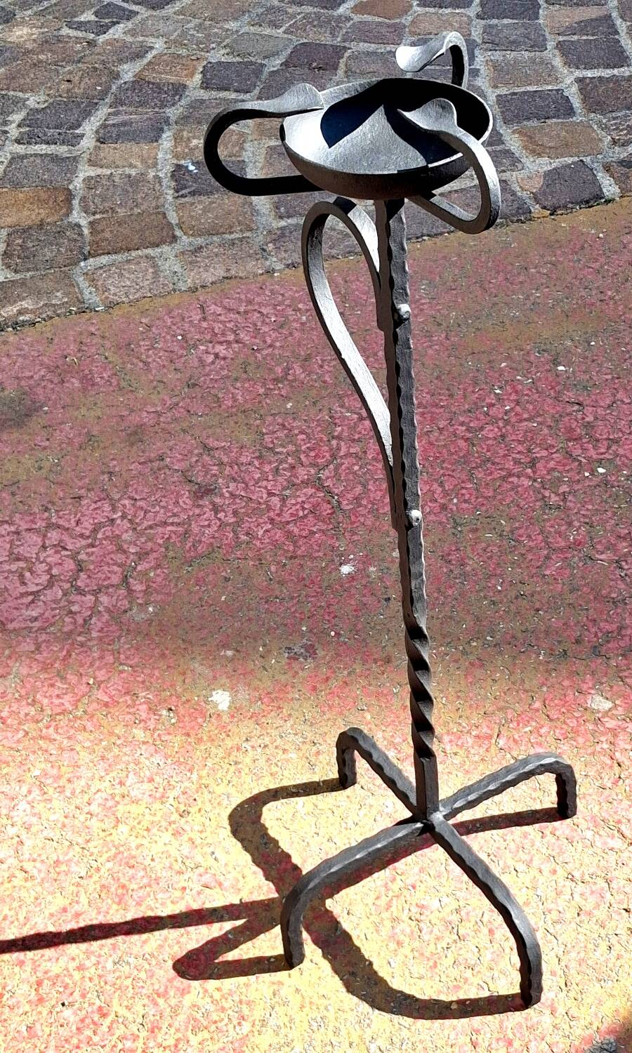 Old ashtray on twisted hammered wrought iron legs, vintage decor.