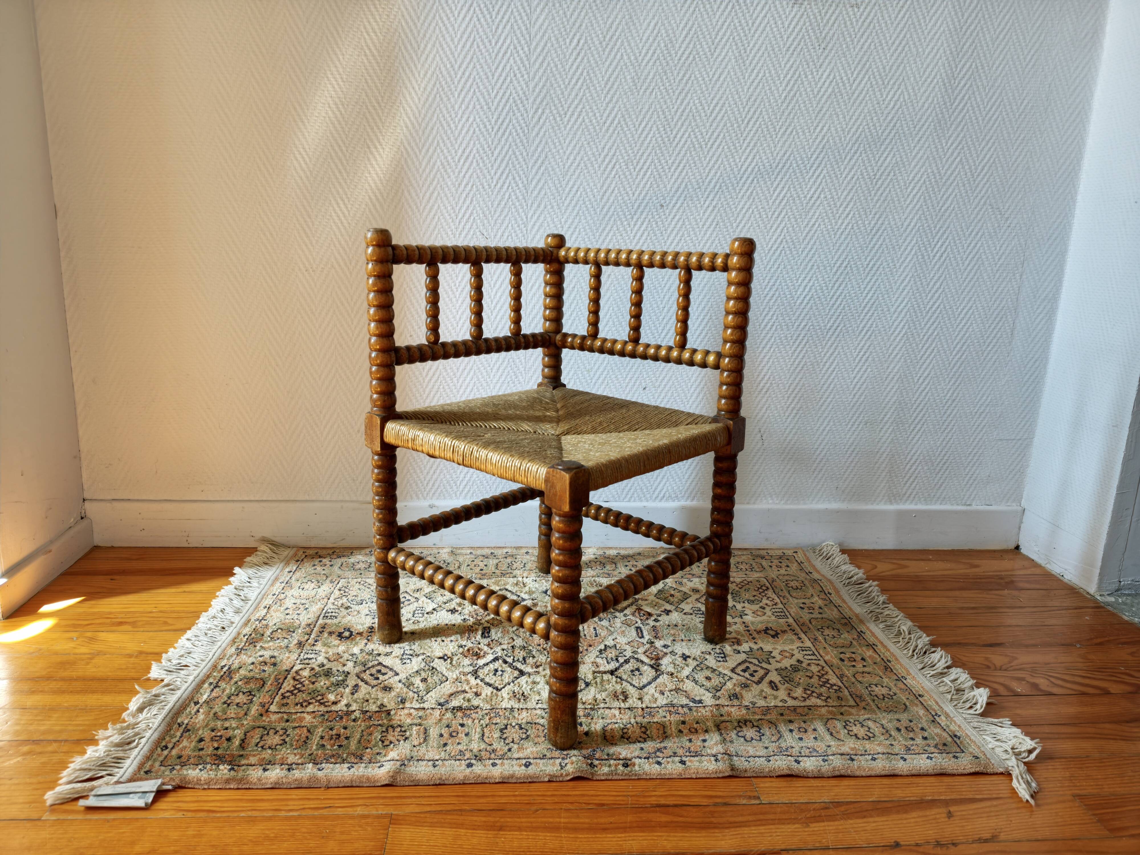 Antique corner chair by the fire with turned wood and straw seat.