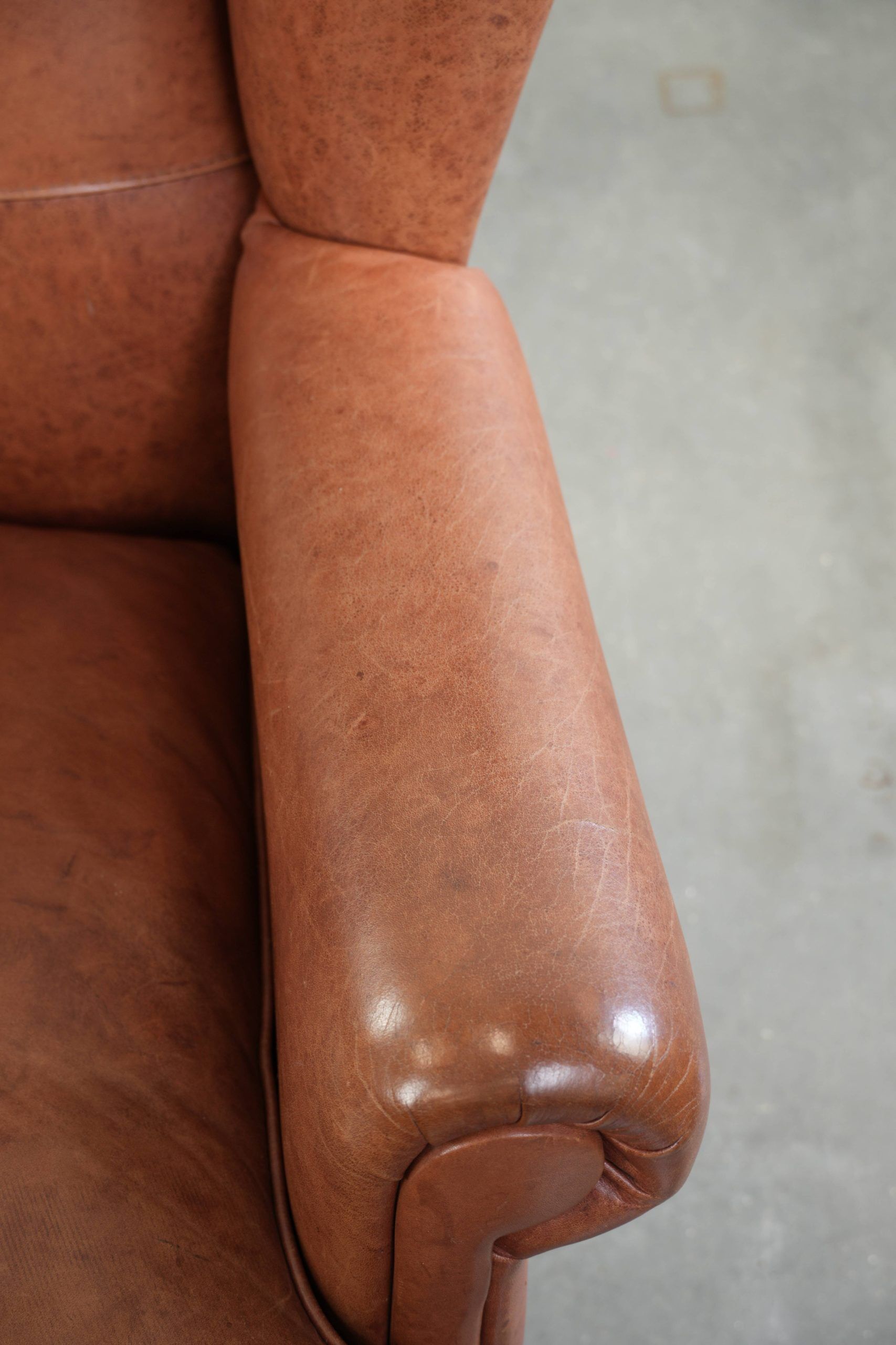 Fauteuil anglais à oreilles de couleur cognac clair en cuir de vache.