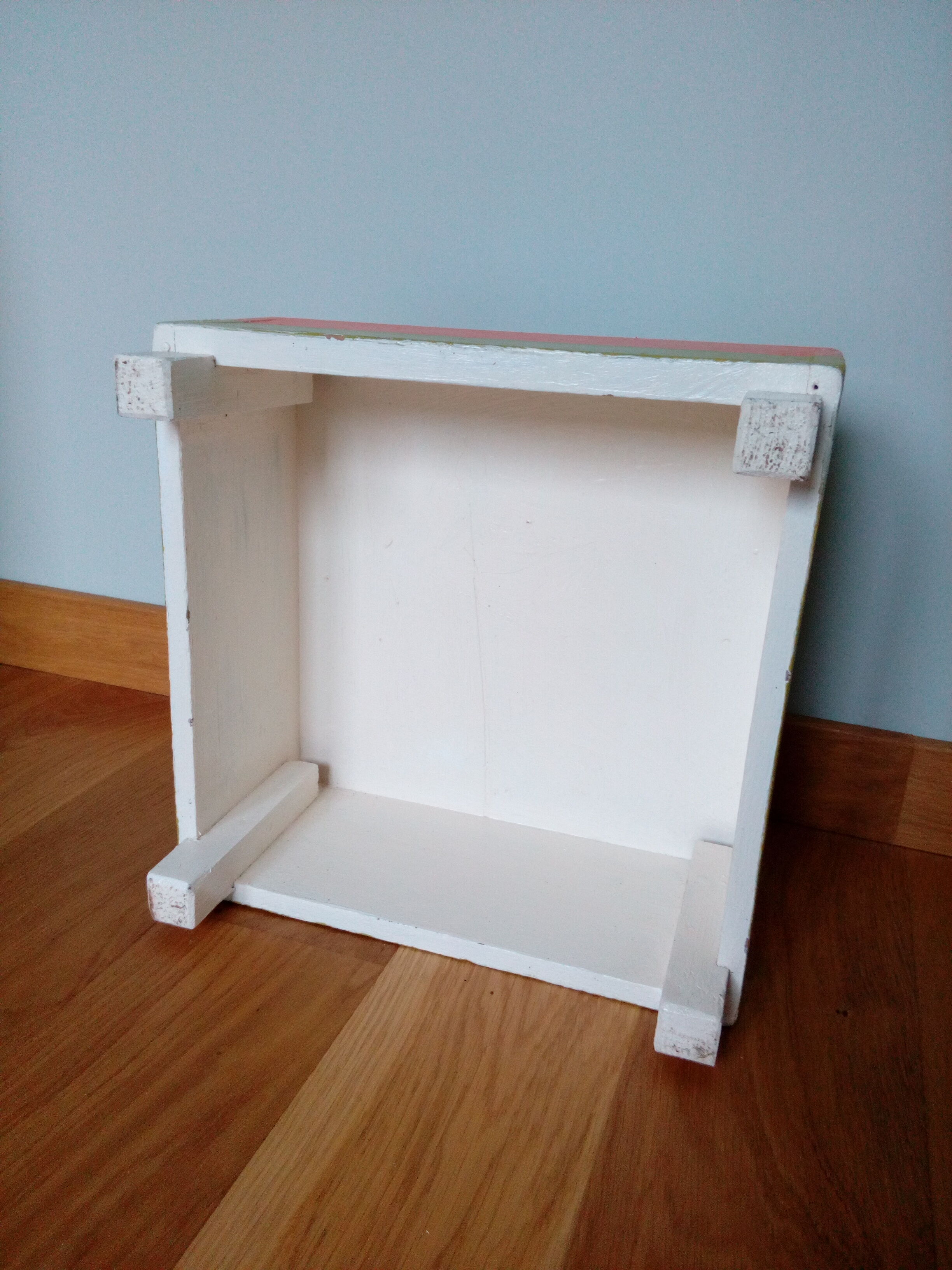 Low wooden stool painted in bright colours