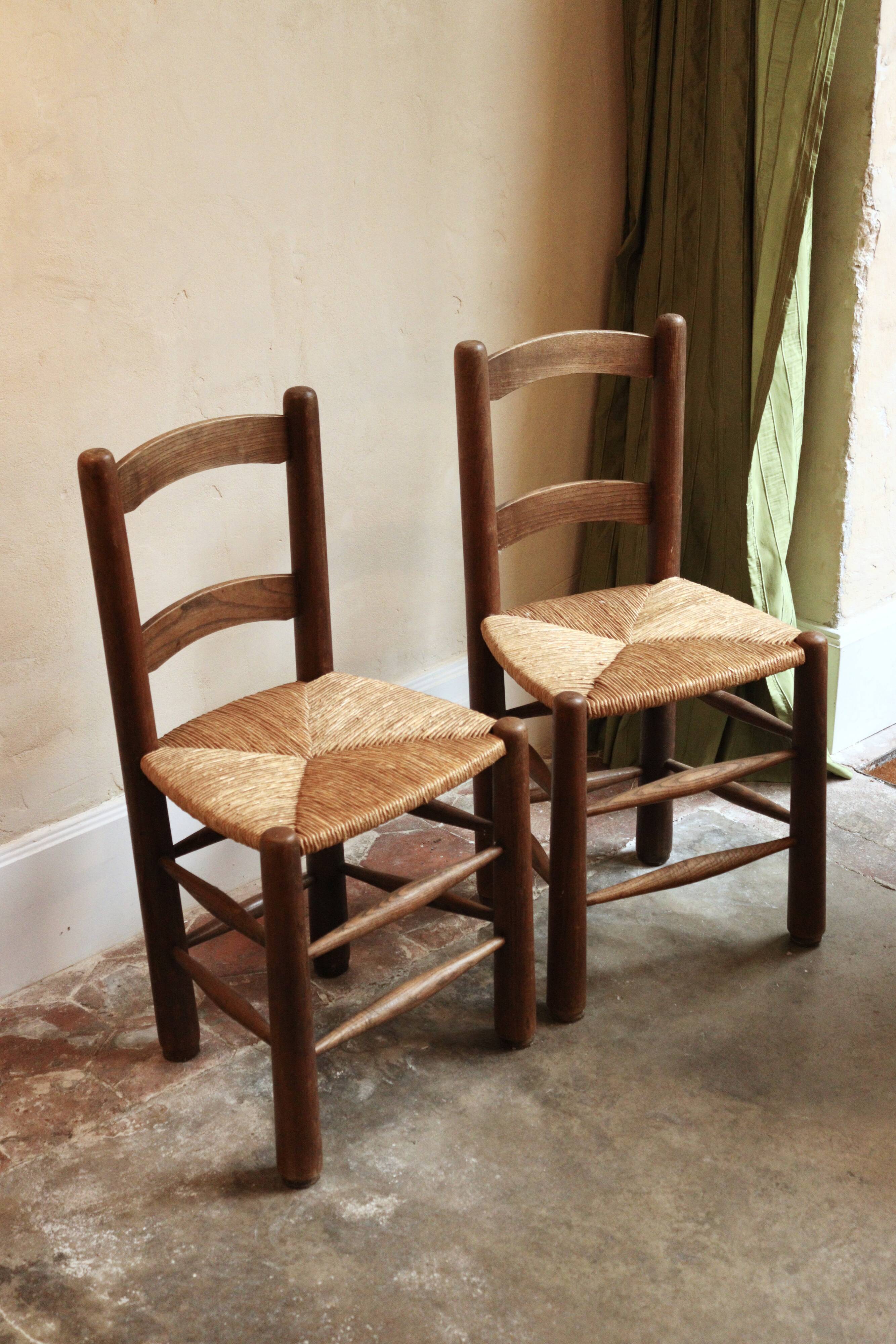 Pair of wooden chairs with woven straw seats.