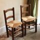 Pair of wooden chairs with woven straw seats.